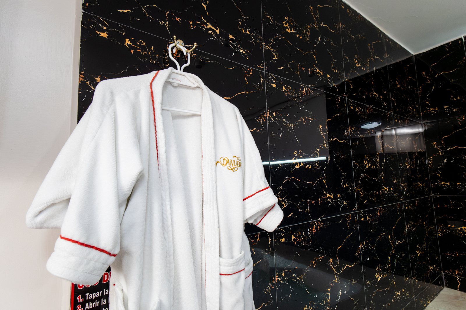 Bata de baño bordada del Hotel Danubio en el baño de mármol negro